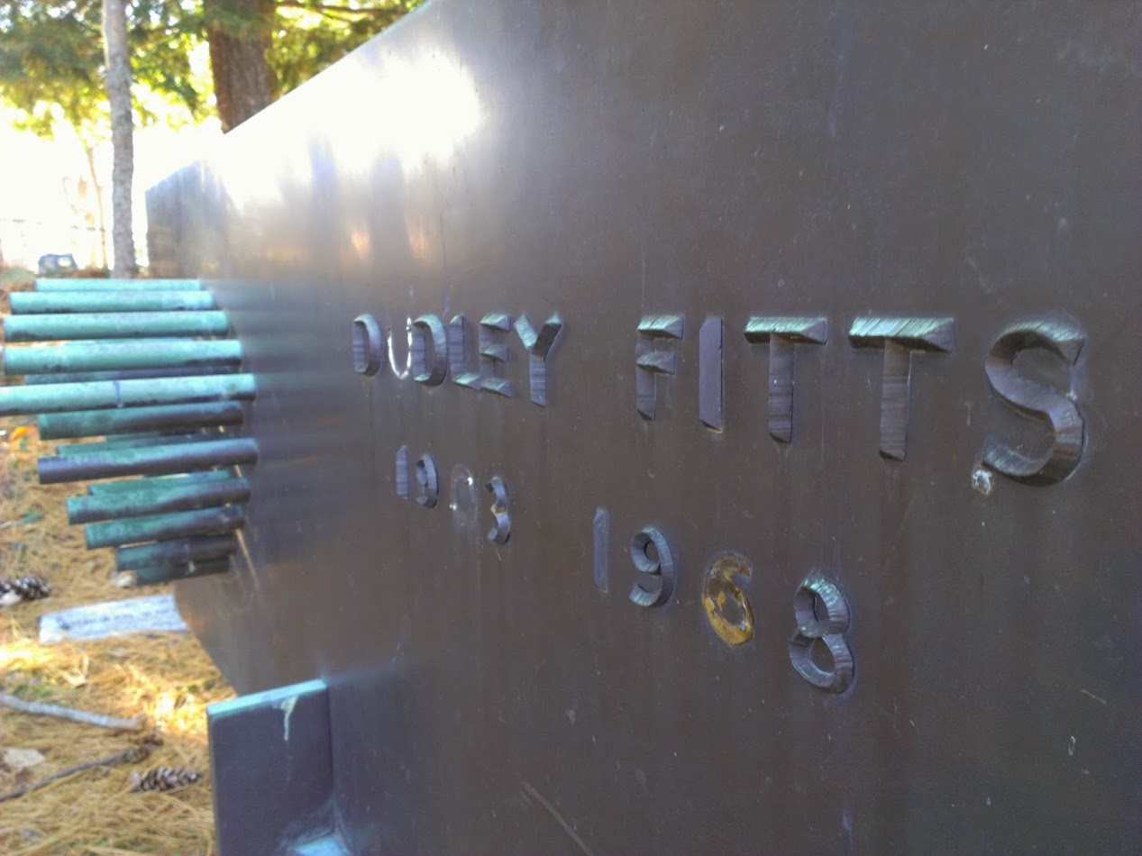 A close-up photograph of the memorial above Dudley Fitts's grave, depicting his name, the embossed dates '1903-1968' (the 0 and 6 have fallen off or eroded), and, to the left of the words, several mysterious protruding poles of various lengths clustered together.