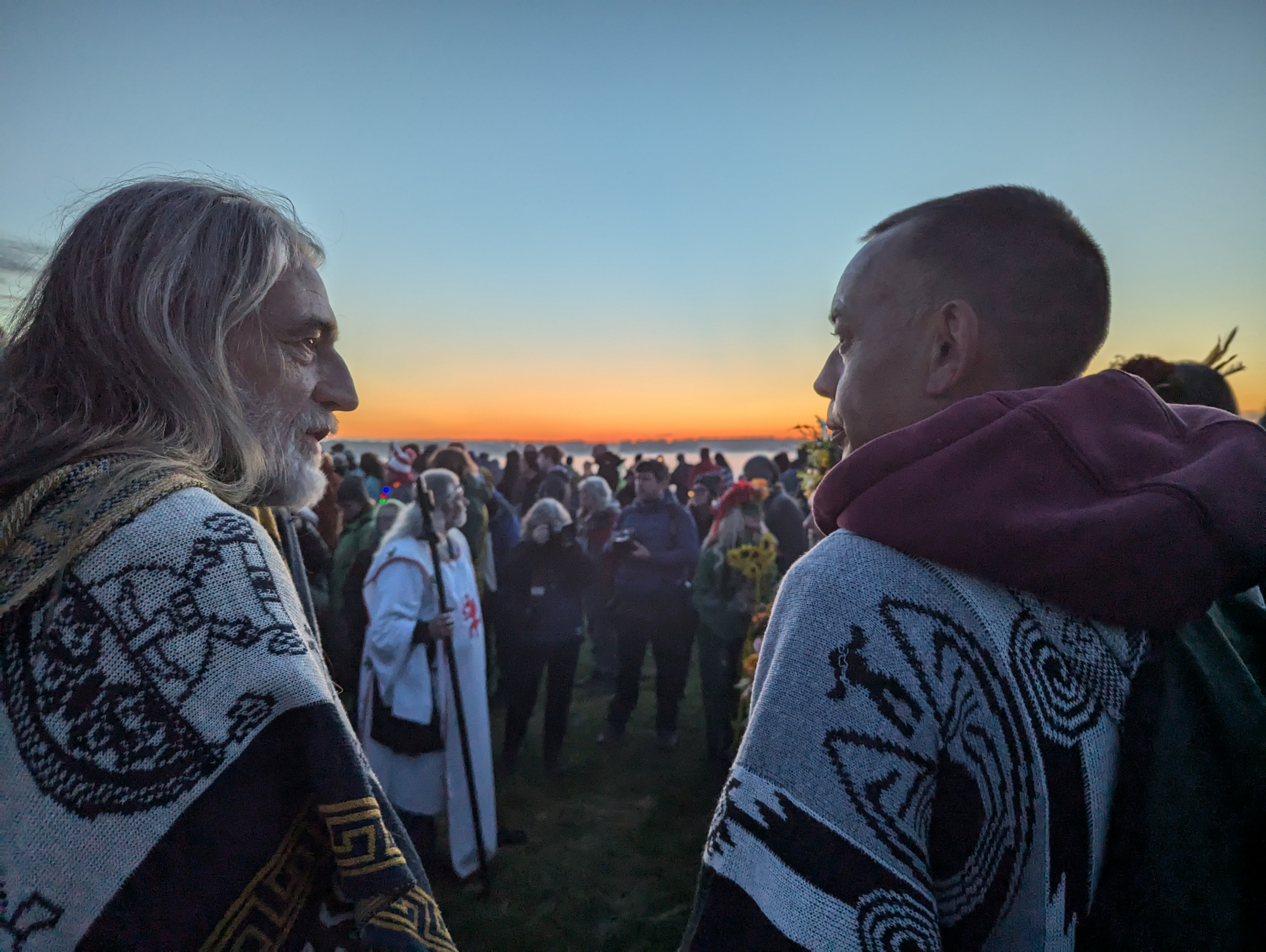 Two druids look on as Arthur Uther Pendragon officiates a Druid ceremony just before sunrise at Stonehenge.