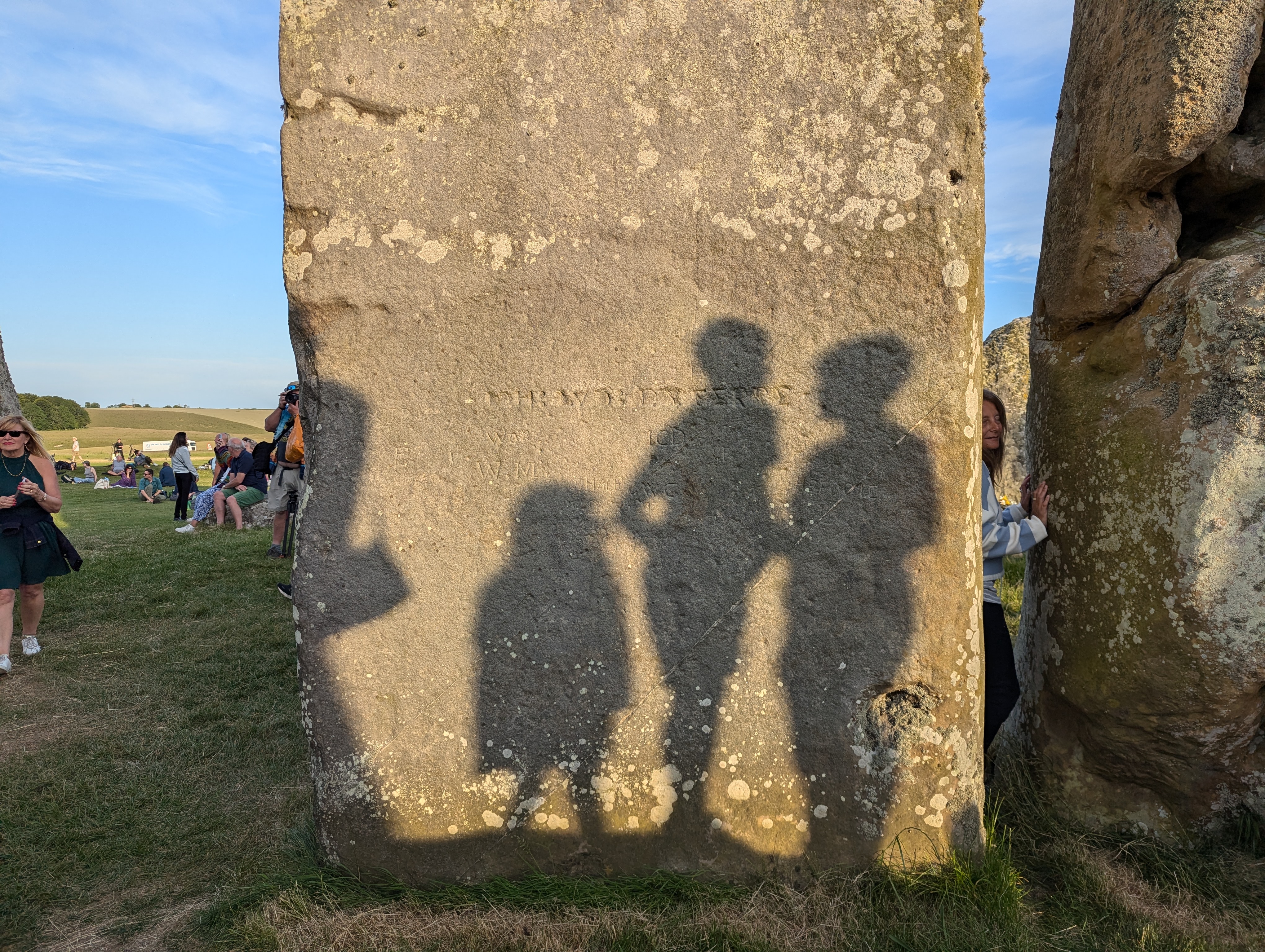 People standing on the altar stone cast their shadows against Trilithons, which have themselves been graffitied time and again.